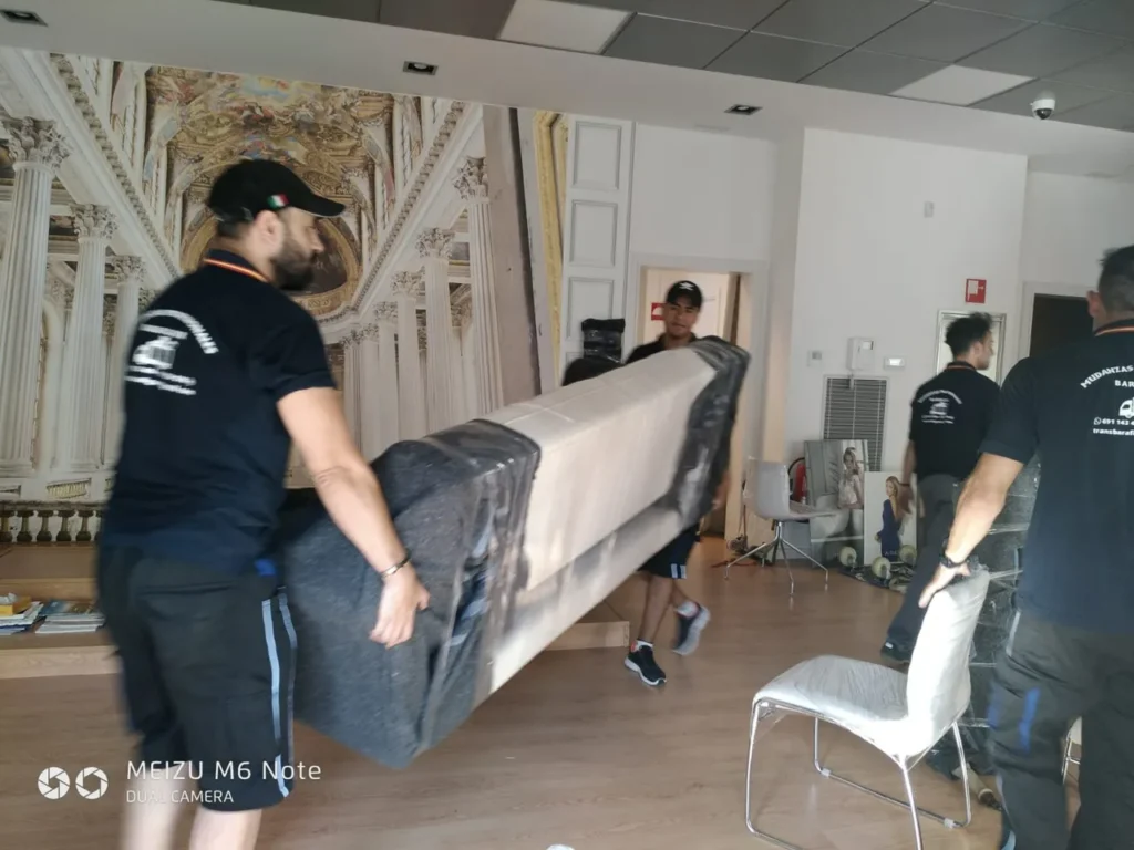 Operarios de Mudanzas Barafiguer trasladando un mueble embalado dentro de un local