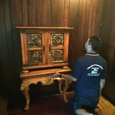 Operario de Mudanzas Barafiguer preparando un mueble antiguo de madera tallada para el traslado