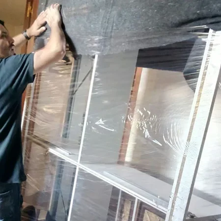 Operario de Mudanzas Barafiguer protegiendo una estantería con film y manta