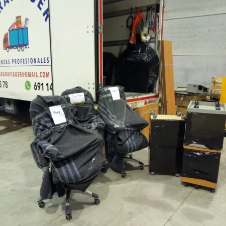Sillas de oficina y archivadores protegidos con mantas junto al camión de Mudanzas Barafiguer