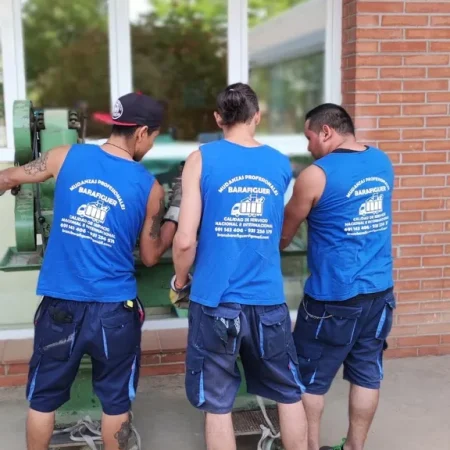 Cuatro operarios de Mudanzas Barafiguer sacando un mueble por la ventana de una casa