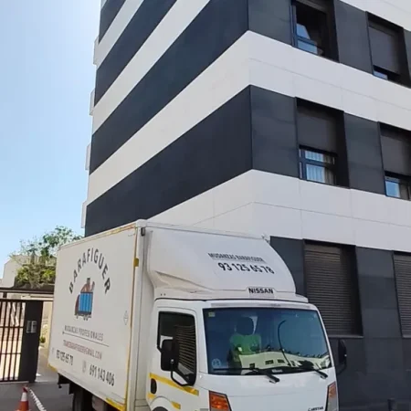 Camión de Mudanzas Barafiguer aparcado con conos frente a un edificio de viviendas